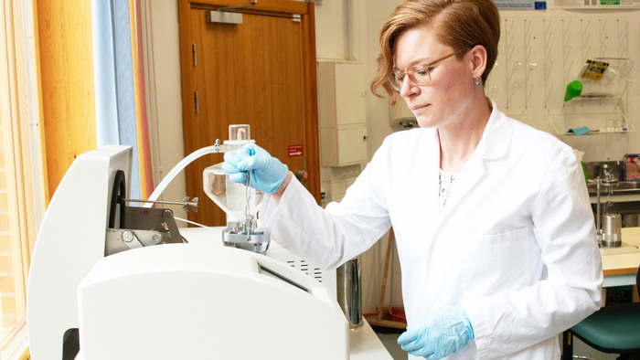 En kvinna i vit rock genomför experiment med en apparat i ett laboratorium.