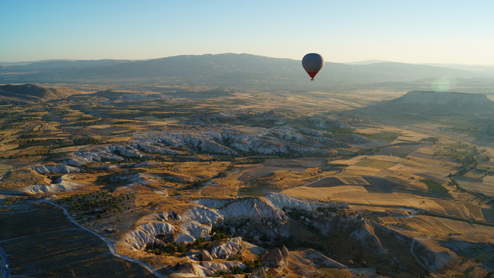 A hot air balloon flies over mountains